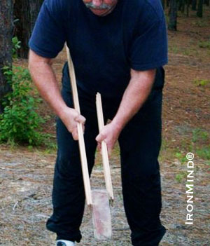 Here John uses a brick instead of a weight plate.  Notice the increased difficulty of the exercise by the placement of the sticks on the brick: the brick will want to wobble and slip free of the sticks; therefore, you will need to exert more pressure to keep it in place.  IronMind® | Photo courtesy of John Brookfield. 